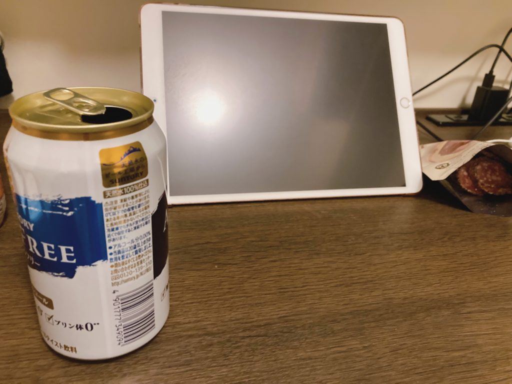 机の上のノンアルビールとiPadとおつまみのサラミ